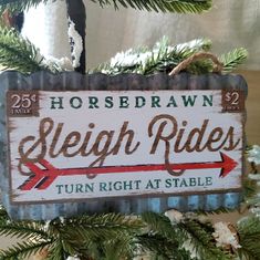 a sign hanging from the side of a christmas tree that reads, horsbee dawn sleigh rides turn right at stable