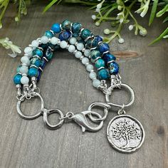 This stunning five strand gemstone bead bracelet is handcrafted with genuine Blue Teal Imperial Jasper round and nugget stones, and tiny Green Moonstone beads, along with silver finish accents, and a large lobster claw clasp, and a Tree of Life charm.  Only high quality genuine stones are used in each unique piece.  This bracelet measures approximately 6.75 inches long.  Sorry - sizing is NOT available on this style. Please message me for special orders.  Imperial Jasper: a spiritual healing stone; encourages tranquility and relaxation; helps with inner peace and stability Green Moonstone: a stone of the goddesses; connects with feminine earth energy; encourages insight Spiritual Multi-strand Hand Wrapped Beaded Bracelets, Spiritual Multi-strand Beaded Bracelets For Jewelry Making, Spiritual Multi-strand Healing Jewelry, Nature-inspired Hand Wrapped Round Beads Jewelry, Spiritual Multi-strand Gemstone Beaded Bracelets, Nickel Free Multi-strand Bracelets For Jewelry Making, Nickel-free Multi-strand Bracelets For Jewelry Making, Multi-strand Beaded Bracelets With Natural Stones As Gift, Green Moonstone