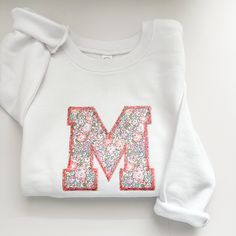 a white sweatshirt with the letter m on it's chest and sequins