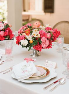 the table is set with pink, orange and white flowers