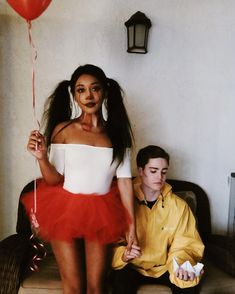 a man sitting next to a woman in a red tutu and holding a balloon