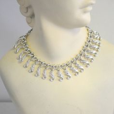 "Vintage 1960s silver tone choker necklace, with a hook clasp and an extender chain.  Made by Sarah Coventry.  The center section is 8\" wide, the extender chain is 6\" long, and the other end 3.25\" long with the hook clasp.  The necklace is 1\" wide at its widest point.  In great condition, with very little wear. We have the matching earrings here: https://www.etsy.com/listing/1006391207/1960s-sarah-coventry-nos-silver-clip?ref=listing_published_alert ---> If you need an order shipped by a par Silver Costume Jewelry Choker, Retro Silver Metal Necklaces, Silver Metal Choker For Costume Jewelry, Retro Silver Metal Necklace, Retro Silver Metal Jewelry, Silver Metal Costume Jewelry Choker, Silver Chain Choker For Formal Occasions, Vintage Silver Choker Necklace, Vintage Sterling Silver Choker In Silver