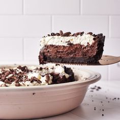 a piece of cake is being lifted by a fork from a bowl with chocolate and whipped cream on it