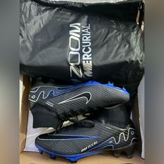 a pair of black and blue soccer cleats in a box with a bag