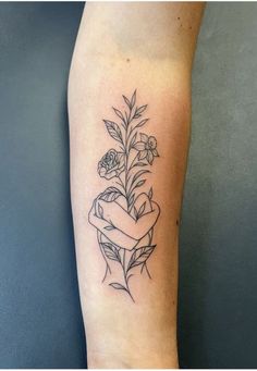 a black and white photo of a tattoo on the arm with flowers, leaves and ribbon