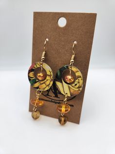 a pair of earrings sitting on top of a cardboard card next to a brown package