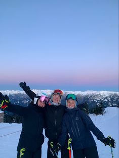 three people standing on top of a snow covered slope