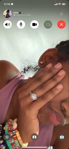 a woman holding her hands to her face while looking at the camera with an earring on