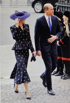 the man and woman are walking down the street wearing matching outfits with hats on their heads