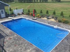 an above ground swimming pool in the middle of a yard with chairs and tables around it