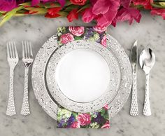 a place setting with flowers and silverware on a marble countertop, along with utensils