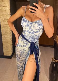 a woman taking a selfie with her cell phone wearing a blue and white dress