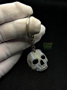 a person wearing a white glove holding a skull keychain