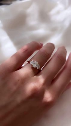 a woman's hand with a diamond ring on top of her finger, and the other hand holding an engagement ring