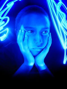 a young man with his hands on his face in front of neon blue lights,