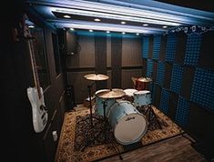 a drum set up in the middle of a room with sound boards on the walls