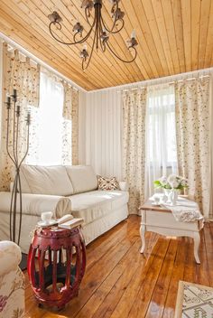 a living room filled with furniture and a chandelier hanging from a wooden ceiling