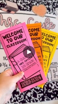 someone is holding up three pink and yellow tickets for the class room, which are decorated with black and white designs