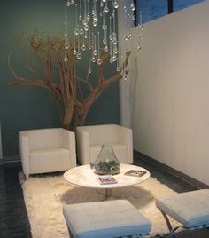 a living room with two white chairs and a tree in the corner on the wall