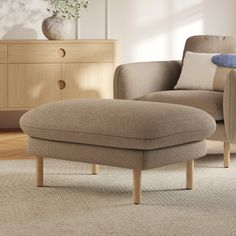 a chair and ottoman in a living room with a vase on the side table next to it