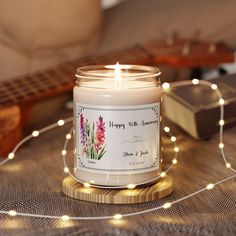 a white candle sitting on top of a wooden table next to a string of lights