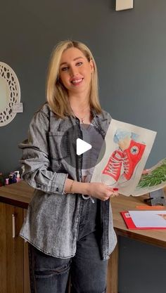 a woman standing in front of a desk holding an open book