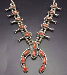 "VINTAGE NAVAJO SQUASH BLOSSOM NECKLACE DESCRIPTION: This stunning necklace features 18 oval cabochons of old red Mediterranean coral. The gemstones are secure in scalloped bezel, on a foundation of heavy gauge vintage sterling silver. Each blossom is framed with an applied leaf, applied raindrops, and a sterling silver swirl. This magnificent necklace will be a valuable addition to your collection of fine vintage Native American jewelry. MEASUREMENTS: Necklace measures 26\" end to end Naja meas Red Southwestern Style Collectible Jewelry, Red Oval Victorian Necklace, Red Victorian Jewelry For Vintage Collection, Heirloom Red Jewelry With Cabochon, Heirloom Red Cabochon Jewelry, Red Vintage Necklace With Cabochon, Vintage Red Cabochon Necklace, Red Vintage Jewelry With Cabochon, Vintage Oval Red Jewelry