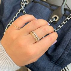 a woman's hand holding onto a chain and wearing a ring with three stones on it