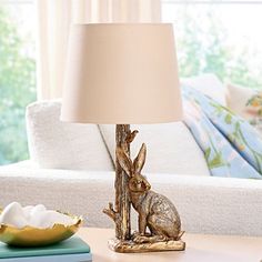 a table with a lamp on it and a bunny figurine next to it