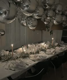 a long table is set with silver plates and place settings for an elegant dinner party