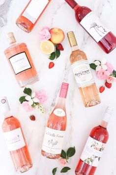 several bottles of wine sitting on top of a marble counter next to flowers and fruit