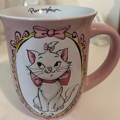 a pink coffee mug with an image of a cat in a bow around its neck