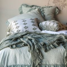 a bed with green ruffled bedspread and pillows