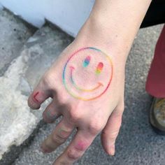 a person's hand with a smiley face painted on the left side of their arm