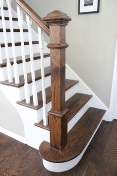 an image of a wooden stair case in the house or office area with wood floors and white railings