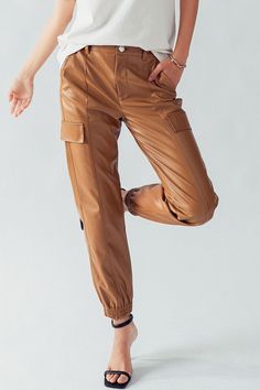 "Elevate your streetwear game with these cute cargo elastic waist faux leather jogger pants. Made from high-quality faux leather, these pants offer a sleek and edgy look while providing comfort with their elastic waistband and relaxed jogger fit. The cargo pockets add a touch of utility and style, perfect for carrying your essentials. Whether you're going for an urban chic look or want to add an edgy element to your outfit, these pants are a must-have. Pair them with a graphic tee and sneakers f Leather Jogger Pants, Trendy Joggers, Leather Joggers, Cozy Tops, Leather Pant, Style Cargo, Edgy Style, Edgy Look, Style Streetwear