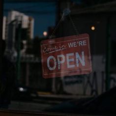 a red open sign hanging from the side of a window