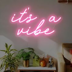 a pink neon sign that says it's a vibe in front of a white wall