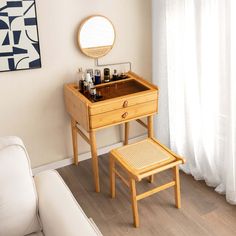 a small wooden table with a mirror and bottles on it next to a white couch