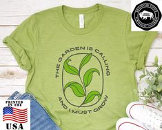 "The Garden Is Calling And I Must Grow is a funny shirt design that's great as a gift or for yourself. Whether you are into gardening, vegetables, succulents, or simply have a green thumb. Also a fun design for vegans who grow their own or support local farmers. Now available in plus sizes! This updated unisex essential fits like a well-loved favorite. Super soft cotton and excellent quality print makes one to fall in love with it over and over again. .: 100% Airlume combed and ringspun cotton ( Green T-shirt With Plant Print For Gardening, Green Tops With Letter Print For Gardening, Green Plants Print T-shirt For Gardening, Casual Green T-shirt For Gardening, Green Relaxed Fit T-shirt For Gardening, Green Graphic Print T-shirt For Gardening, Mid Century Furnishings, Gardening Vegetables, Support Local Farmers