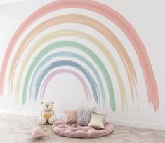 a rainbow painted on the wall in a child's room with a teddy bear