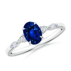 an oval blue sapphire and diamond ring with two side stones on the band, set in 18k white gold