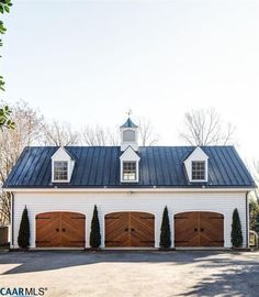 a large white house with three brown garage doors