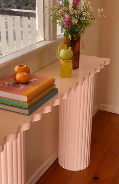 a vase with flowers and books sitting on a table next to a window sill