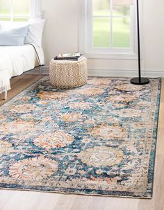 an area rug with blue, orange and yellow flowers on it in front of a window