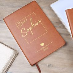 a brown book with writing on it sitting next to two notebooks and a pen