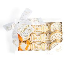 an open box of decorated cookies with white icing and gold foil on the top