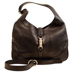 A Gucci Jackie made of black leather with light gold toned hardware. The interior is lined with beige fabric, and next to the major compartment it features three side pockets of which one has a zipper. The bag can be closed with the piston closure. The bag can be worn as a shoulder strap with the short strap (max. 48 cm), or as a crossbody bag with the additional strap (total max. ca. 100 cm). The bag will be delivered with cards, and without the dust bag. The condition of the bag is very good w Gucci Crossbody Bag Vintage, Burberry Crossbody Bag, Gucci Brand, Gucci Outfits, Gucci Tote, Beige Fabric, Vintage Louis Vuitton, Jack Black, Leather Shops