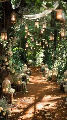 an outdoor wedding ceremony with lanterns and flowers on the path leading to the aisle that is lined with greenery