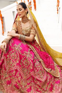 Orange and Pink Lehenga Choli Pakistani Bridal Wear is a Heavy worked shocking pink raw silk lehenga, with rust net heavy choli. Paired with golden olive color organza dupatta featuring border and jaal. Could be paired with two dupattas as shown. Pink chiffon dupatta with heavy border could also all around accentuates the look. Pink Lehenga Choli: Orange is just associated with mehndi as the sun is associated with brightness. NameerabyFarooq presents the bright pink bridal mehndi outfit which la Mehndi Outfit Bridal, Lehenga Choli Pakistani, Pink Lehenga Choli, Olive Colour, Mehndi Outfit, Ceremonial Clothing, Raw Silk Lehenga, Bridal Dupatta, Mehndi Brides